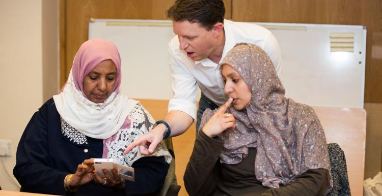 Two women and a man looking at a mobile phone