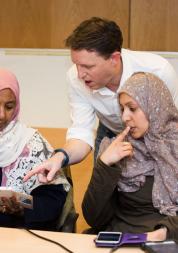 Two women and a man looking at a mobile phone